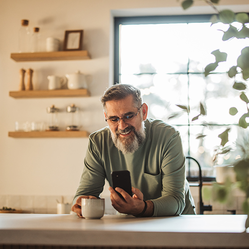 man looking at phone holding a coffee cup