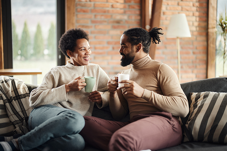 man and woman holding cups sitting on a couch
