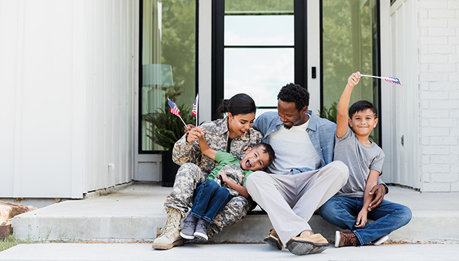 Woman in military uniform sitting on porch with a man and children