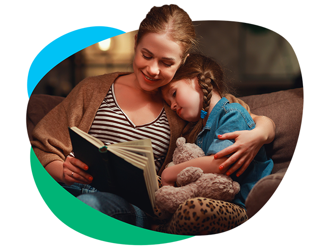 Woman holding a young girl while reading a book