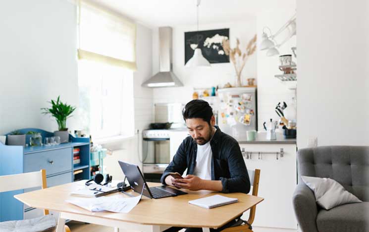 man working at desk on phone and laptop