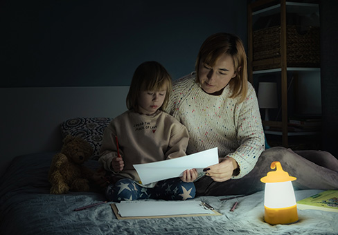 Woman and girl sitting on a bed with a lamp