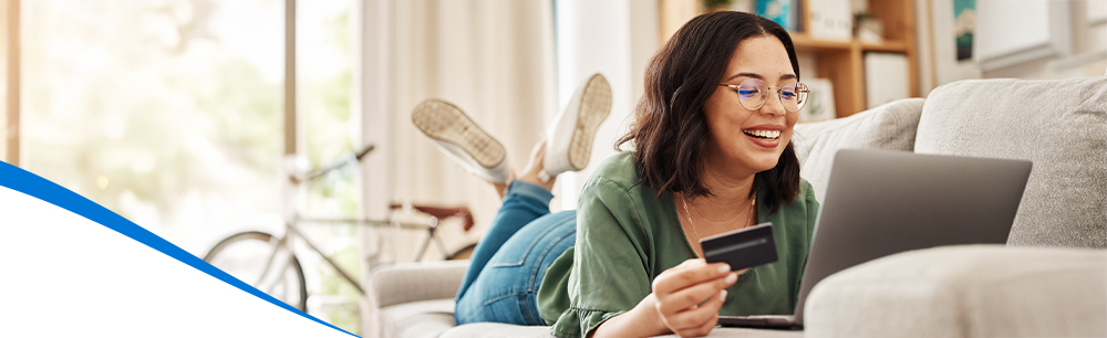Woman holding credit card looking at laptop