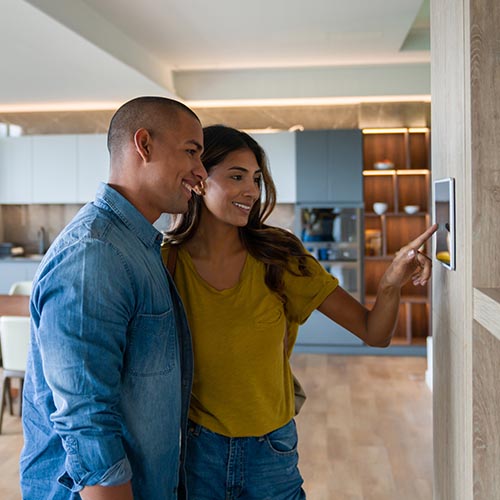 Man with woman touching a thermostat