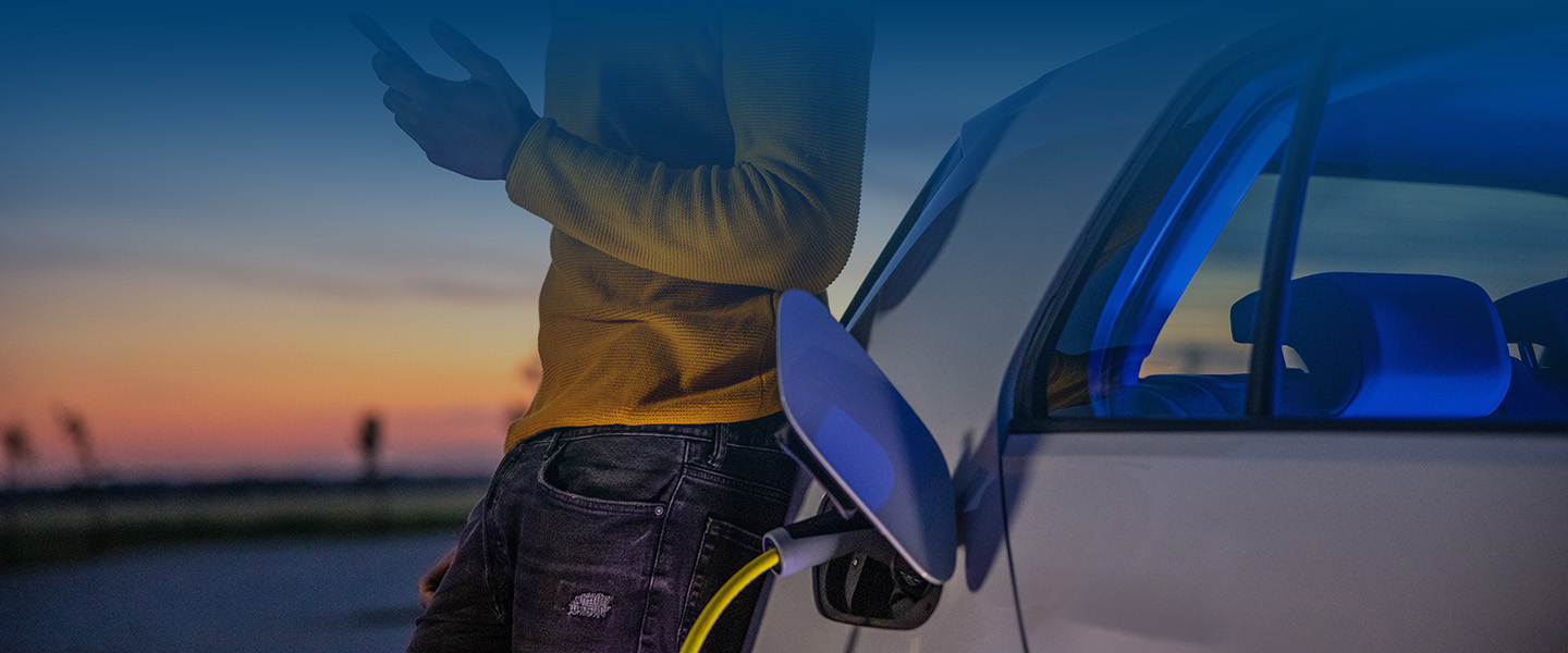 Man using mobile phone while he is waiting for his electric car to be charged