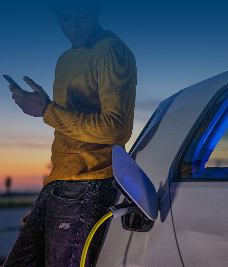 Man using mobile phone while he is waiting for his electric car to be charged